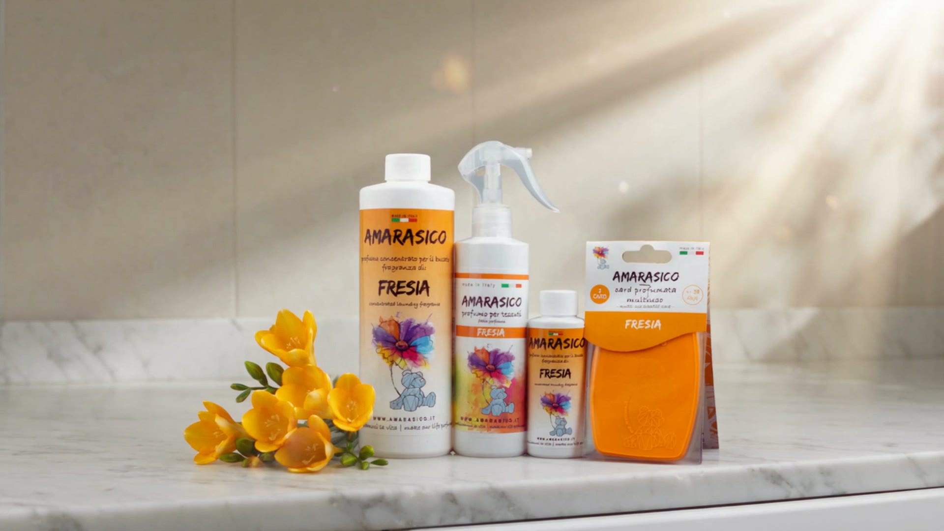 Flaconi Fresia, spray e card profumata Amarasico su un piano di marmo con fresie gialle