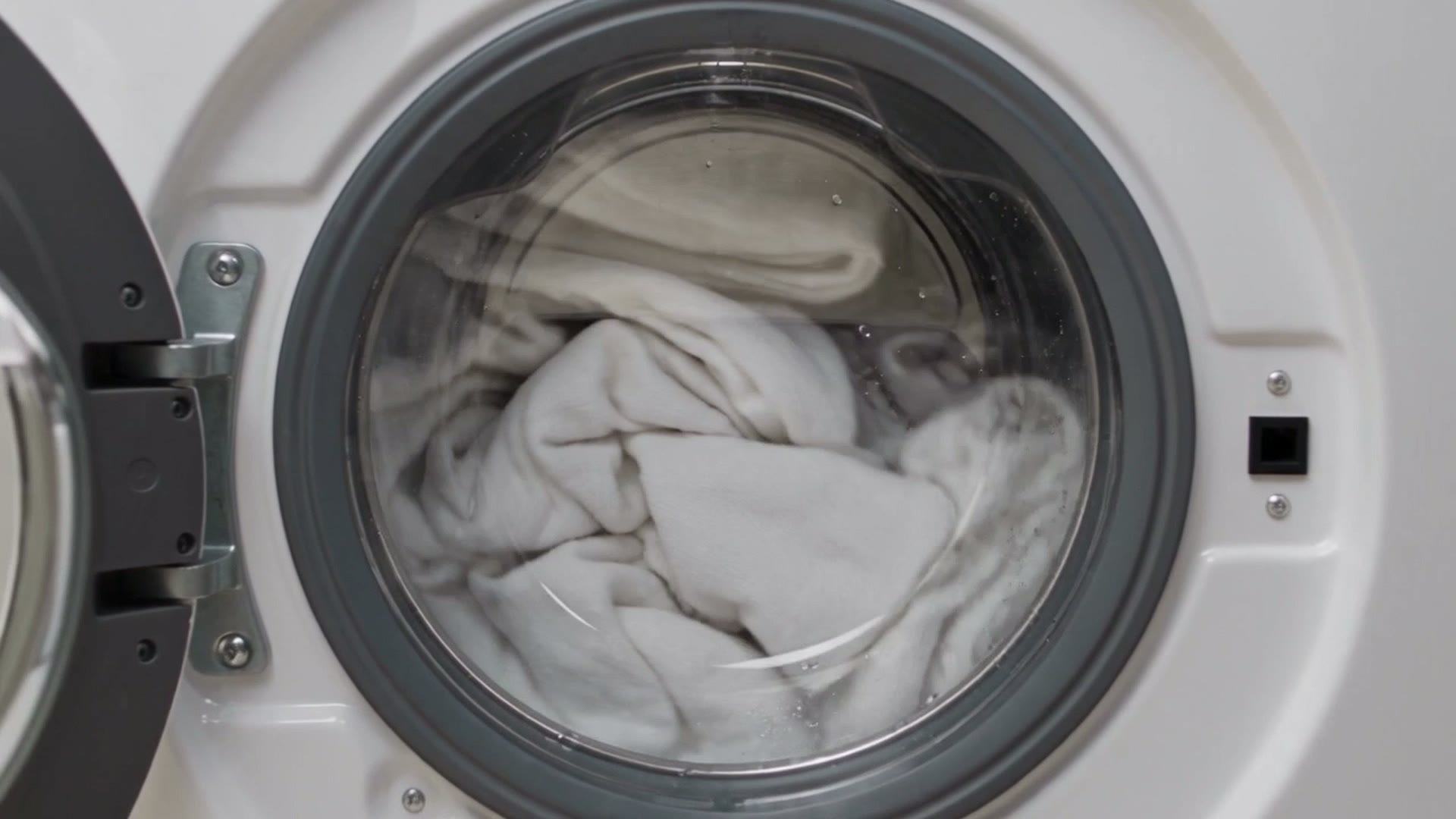 L'oblò di una lavatrice con il bucato bianco che gira