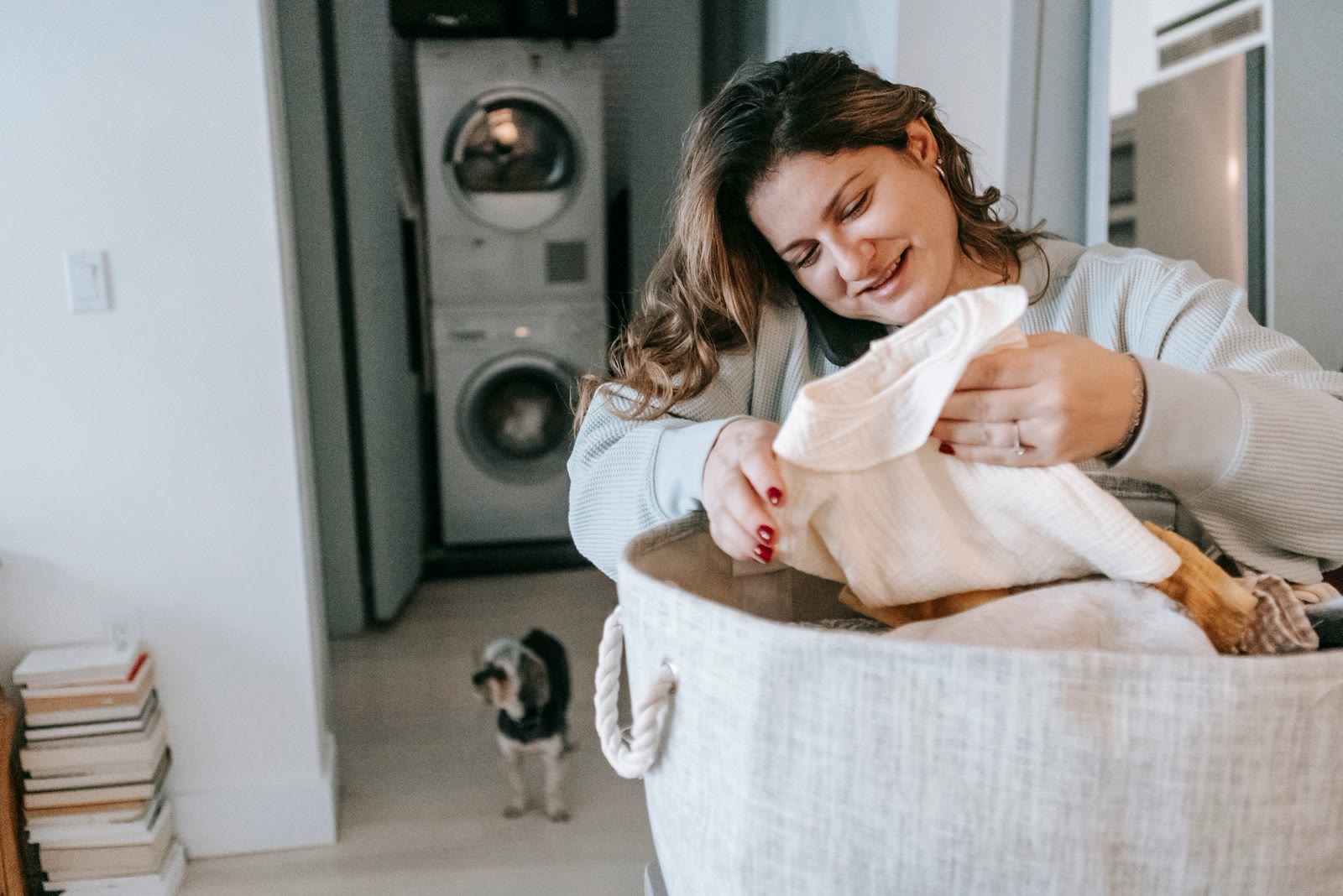 A woman with a basket of clean laundry in a bright laundry room